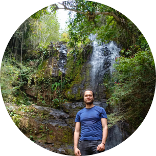 Persona mirando a la cámara con una cascada de fondo y árboles al rededor